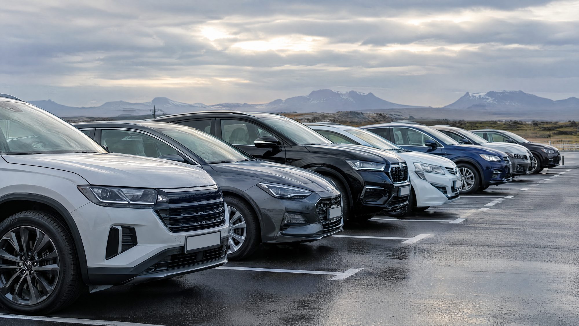 Röð bíla í stæðum Key Drop við Keflavíkurflugvöll, íslensk fjöll í baksýn.